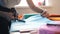 Seamstress cuts blue fabric piece with scissors on desk