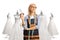 Seamstress holding scissors in front of bridal gowns and thinking