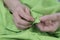 Seamstress makes buttonholes for buttons to green shirt