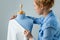 Seamstress measuring beautiful fabric on blue tailor dummy in her workshop.