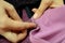 Seamstress prepares knitwear for sewing clothes. Female hands with a pin stab black and pink fabric on the sewing table.