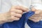 Seamstress sews the button to a blue pants