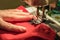 Seamstress sews clothes made of red cloth on a sewing machine