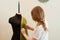 Seamstress standing and straightening green cloth on mannequin in sewing studio