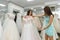 Seamstress or wedding consultant helping bride in salon