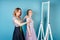 Seamstress woman and bride discuss the details of wedding dress in the studio on a blue background . tailor dressmaker