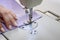 Seamstress works on a sewing machine. The girl sews and holds a lilac cloth