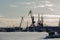 Seaport at sunny winter day - cargo cranes in ice harbor, silhouette