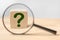 Search for an answer to question. Magnifying glass with question mark in focus on wooden cube. Research, searching or