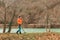 Search With A Metal Detector. A young woman in an orange jacket is looking for lost artifacts along the river. Copy space