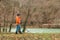 Search With A Metal Detector. A young woman in an orange jacket is looking for lost artifacts along the river. Hobbies and