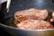 Seared fillets of beef steak cooking in a frying pan.