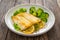 Seared halibut fillet, sliced lemon and boiled broccoli on wooden table