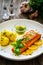 Seared salmon steak with boiled potatoes and lemon served on wooden table