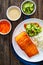 Seared salmon steak with boiled white rice and sliced cucumber on wooden table