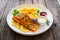 Seared salmon steak with French fries and fresh vegetables served on wooden table