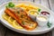 Seared salmon steak with French fries and fresh vegetables served on wooden table