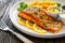 Seared salmon steak with French fries and fresh vegetables served on wooden table