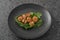 Seared scallops on pile of spinach on black plate closeup
