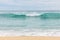 Seascape background. Sandy beach, milky foam waves, blue ocean. Scenic waterscape. Horizon line. Cloudy sky. Nature and