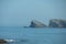 seascape with a beach and rocky islets in the background on a sunny day with fog on the horizon