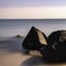 Seascape with black triangular and round boulders on the beach at low tide