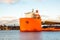 Seascape closeup side view of a large orange semi-submersible heavy-lift ship with large load entering harbor in Stockholm Sweden.