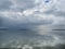 Seascape with clouds, distant shore, blue sky showing through