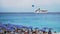 Seascape with a cruise liner, a parachute and people relaxing under striped beach umbrellas on the beach, Nice, France.