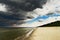 Seascape with dark, dramatic, stormy cumulonimbus cloud formation over the beach at Baltic sea.