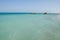Seascape: in the distance a yacht in crystal clear turquoise water and a pier
