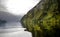 Seascape in Doubtful Sound Fiord, New Zealand, green costline and reflection in a wather, cloudy weather