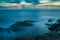 Seascape with dramatic wave and rock in sunset