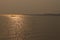 Seascape, lonely boat with sailor in a calm sea at beautiful sunset with sun reflection in the water