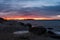 Seascape with orange clouds and rocks on the beach in the forground