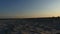 A seascape with sandy beach and calm sea waters at sunset