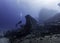 Seascape of a scuba diver swimming in the distance over a very large ship wreck