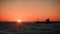 Seascape. The ship is heading towards the setting sun. The sun sinks into the sea beyond the horizon. The sky is orange