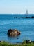 A seascape from the shore with sailboats sailing across the horizon