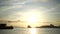 Seascape with silhouettes of fishermen and a ship at sunset.