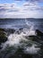 Seascape with Splashing Tidal Waves and Stormy Clouds over the Black Jetty Rocks