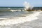 Seascape with stormy waves and old stone pier. Water splashes