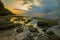 Seascape. Sunset at the beach. Ocean low tide. Rocks with green seaweeds. Cloudy sky. Horizontal background banner. Thomas beach,