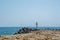 Seascape, view of a big concrete cross on the bay, birds flying, blue waters and sky, breakwaters, summer