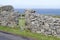 Seascape view of a gate and stone wall along a road on the rugged terrain of Inishmore island in Ireland