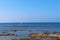 Seascape view of Mediterranean coast with a heron on a rock and a boat on the horizon, Acre, Israel