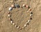 Seashell heart shape on the sand beach.