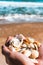 Seashells in hands on the background of the sea, the concept of recreation