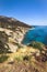 Seashore coastline with beach and rocks and rocky slope of the Island of Elba in Italy. Many people on the beach sunbathing. Blue