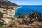 Seashore coastline with beach and rocks and rocky slope of the Island of Elba in Italy. Many people on the beach sunbathing. Blue